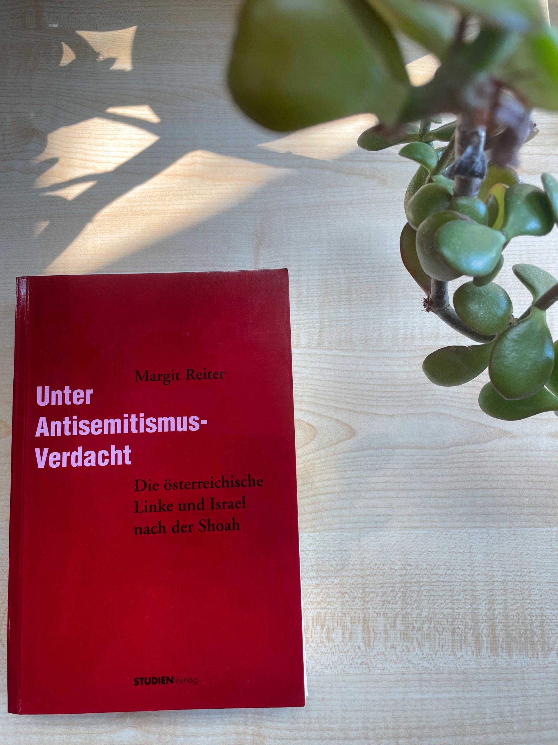 Fotografie des Buches Unter Antisemitismus-Verdacht von Margit Reiter. In der oberen rechten Ecke ist eine Pflanze zu sehen, die in das Bild ragt.